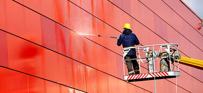 Employee pressure washing a building exterior